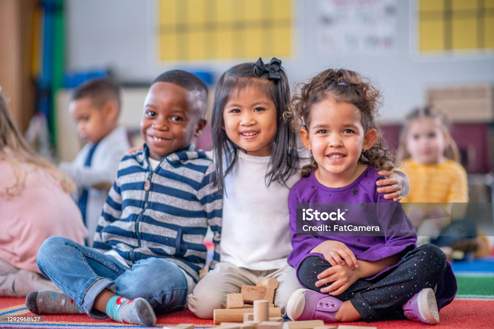 Three children sitting on the floor in a classroom