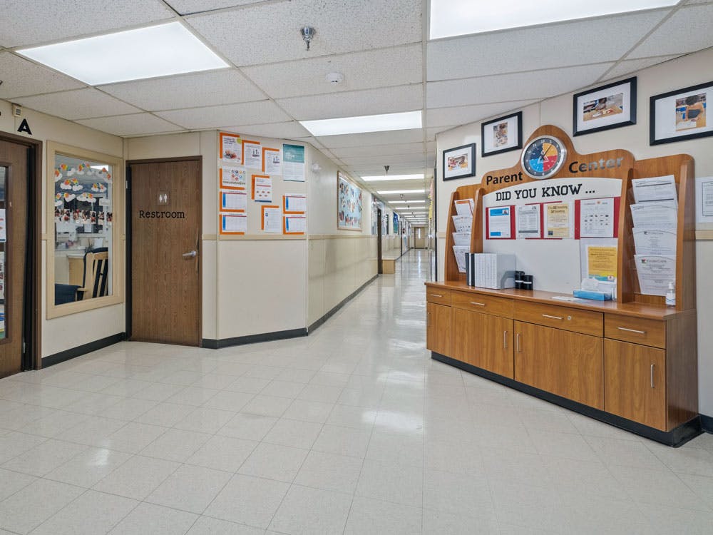 Long hallway with a restroom door, window to a room, and a parent center display