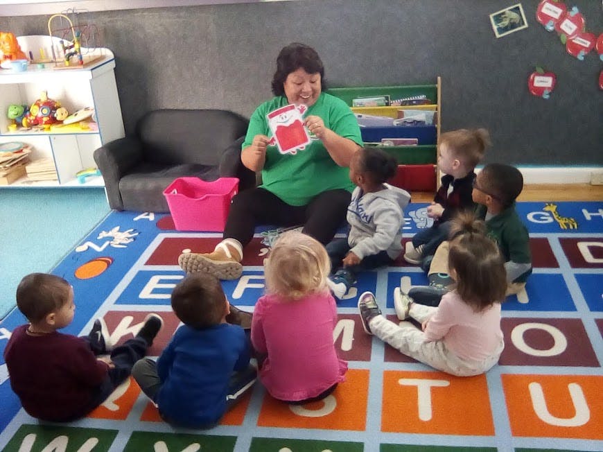 Person reading a book to a group of children in a classroom