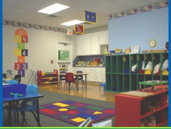 Classroom with colorful rug, tables, chairs, and storage cubbies
