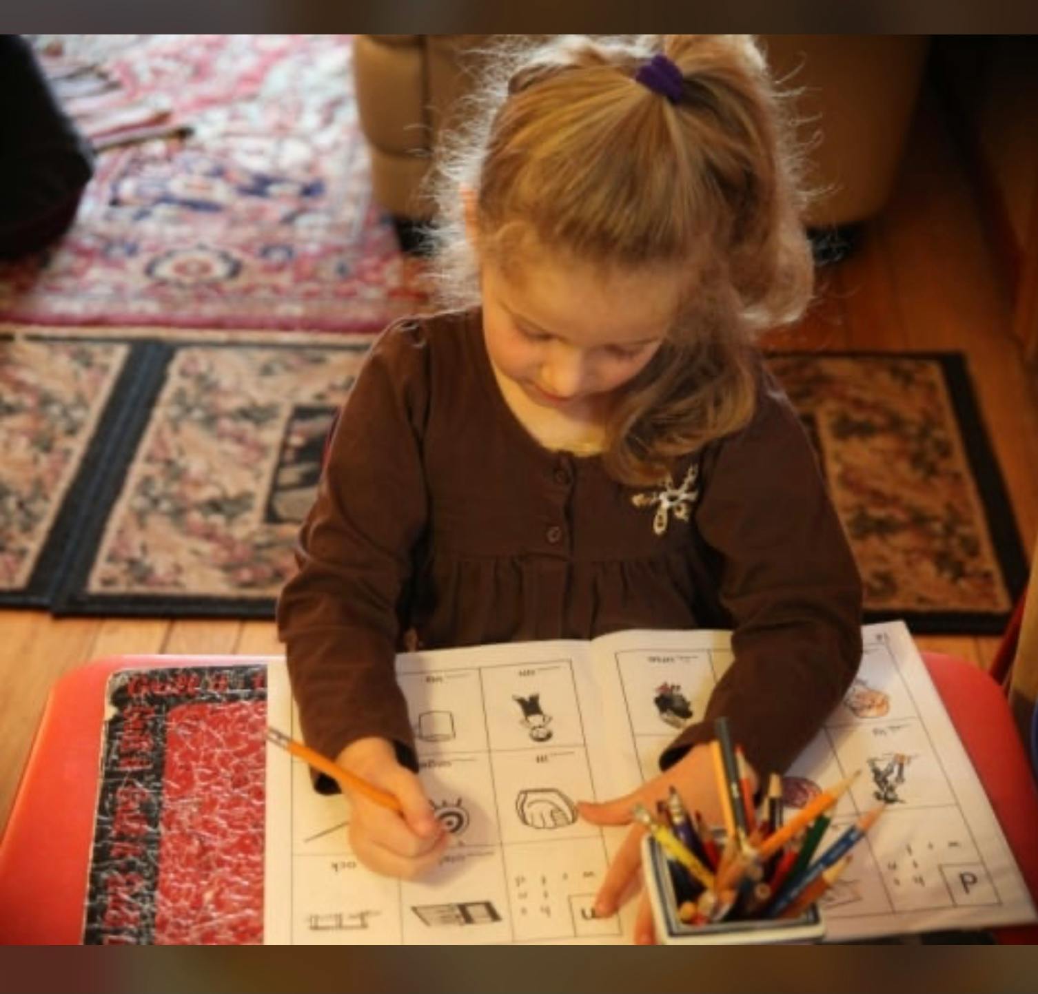 Child coloring in a workbook with colored pencils