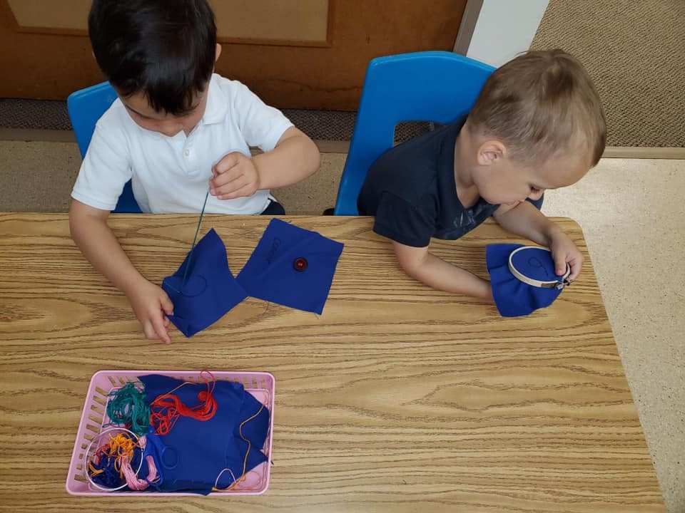 Two children sewing at a table
