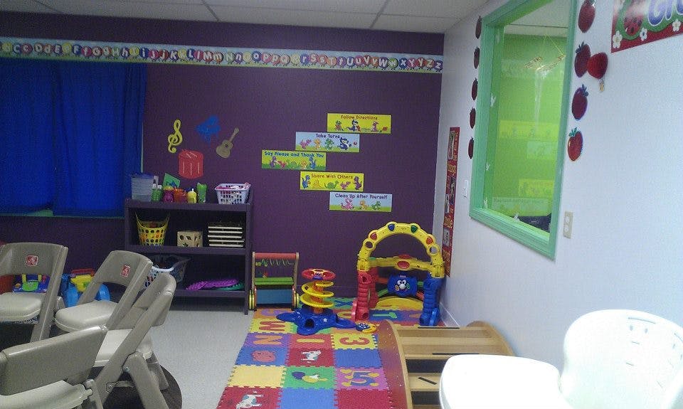 Playroom with colorful mat, toys, and small chairs