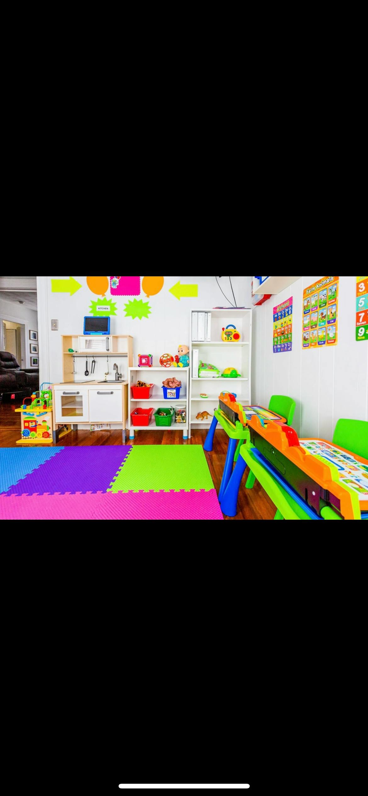 Playroom with colorful floor mats, toy kitchen, and activity table