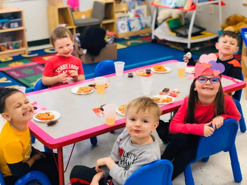 Children sitting at a table with snacks in a classroom