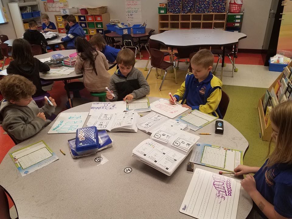 Children working on schoolwork at tables in a classroom