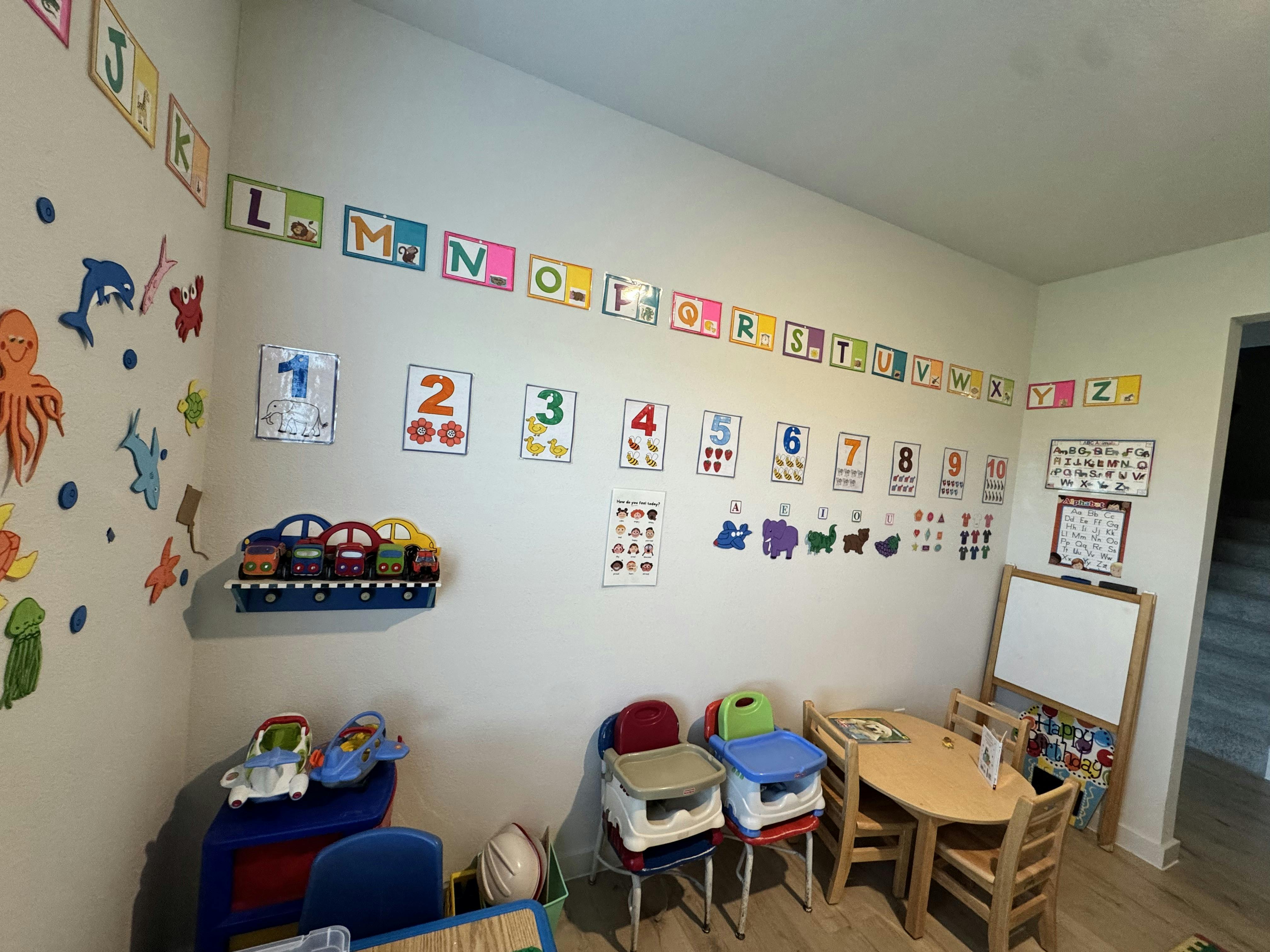 Classroom with alphabet and number charts on the wall, small tables and chairs