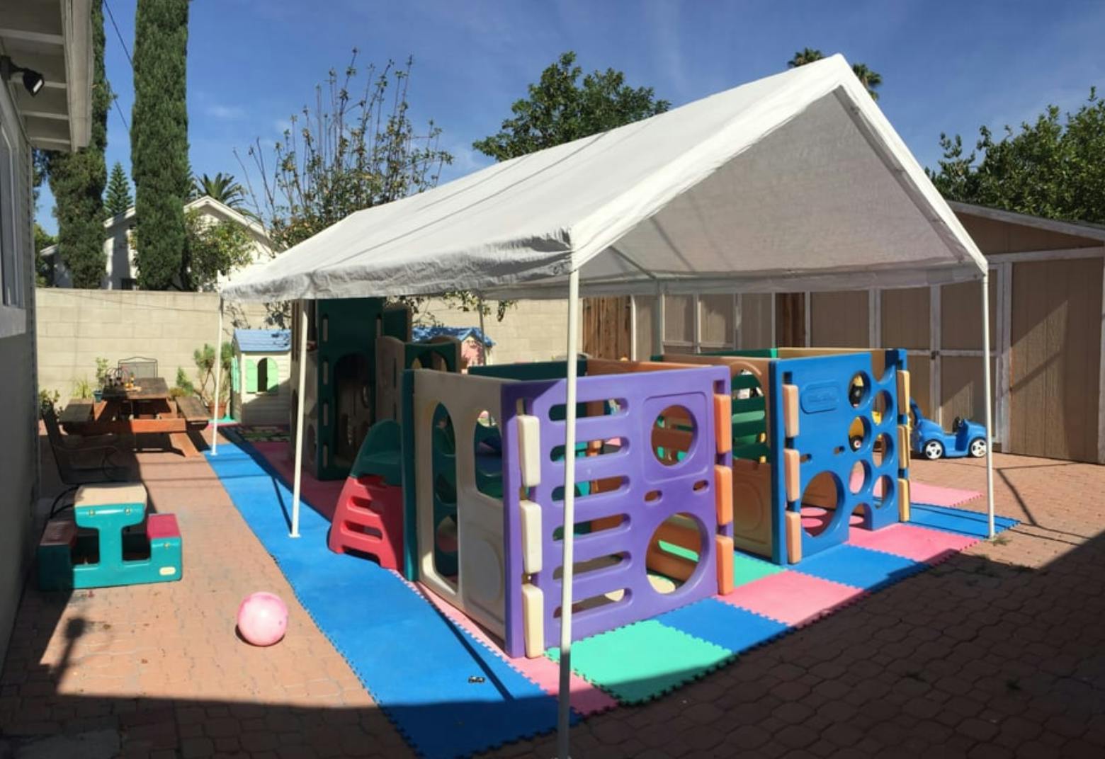 Outdoor play area with a white canopy covering colorful play structures