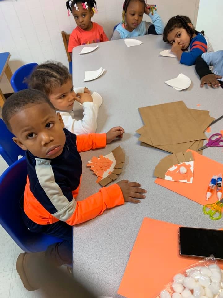 Children sitting at a table with craft supplies
