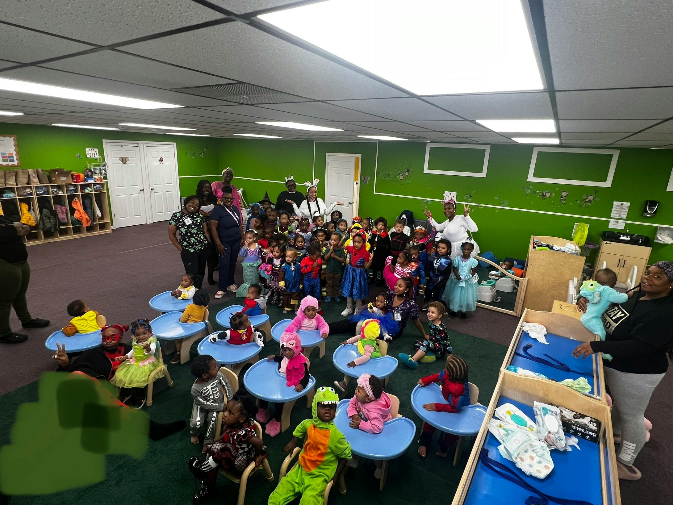 Group of adults and children in a classroom with small tables