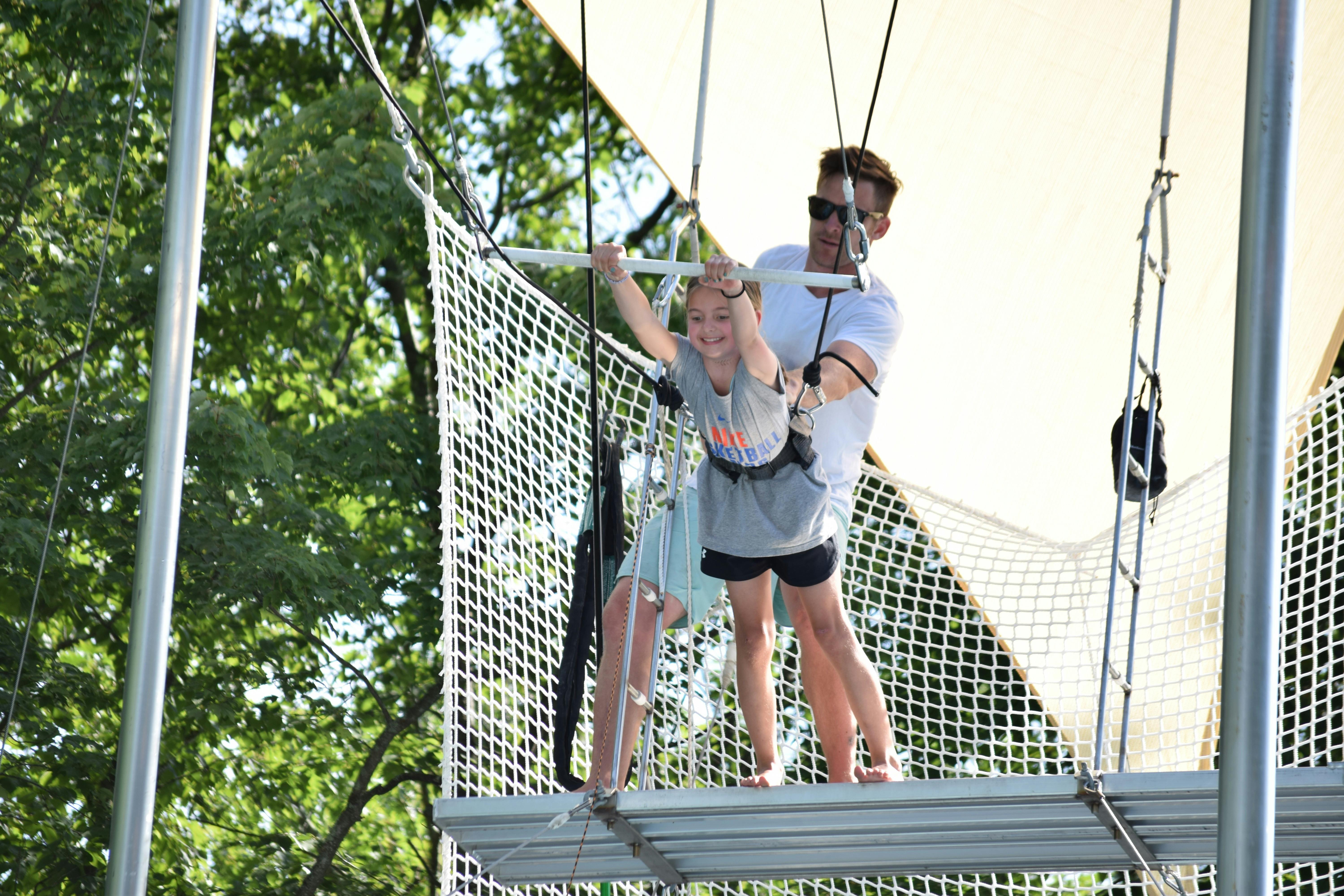 Adult helping a child on a trapeze