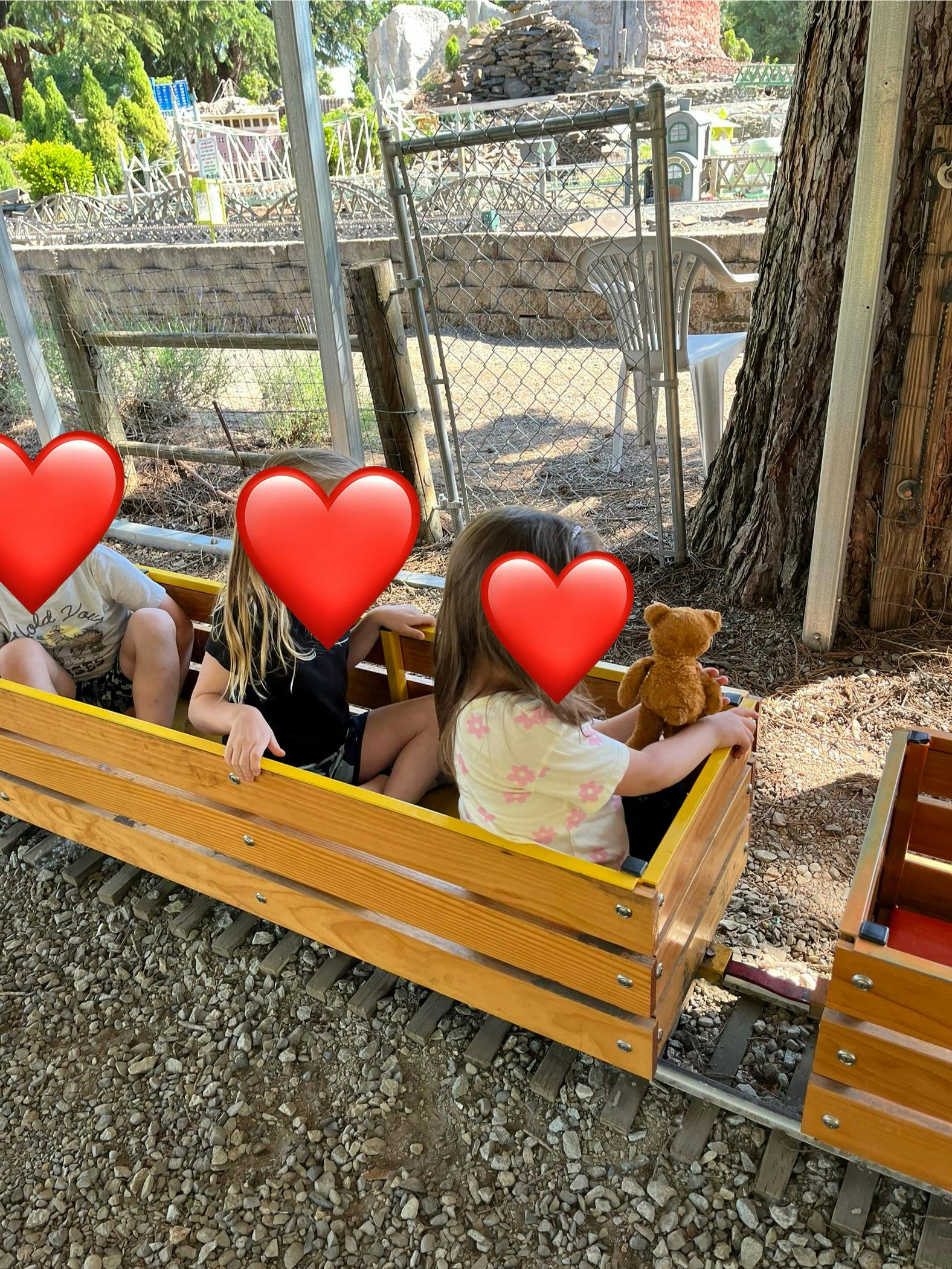 Three children riding in a wooden miniature train car