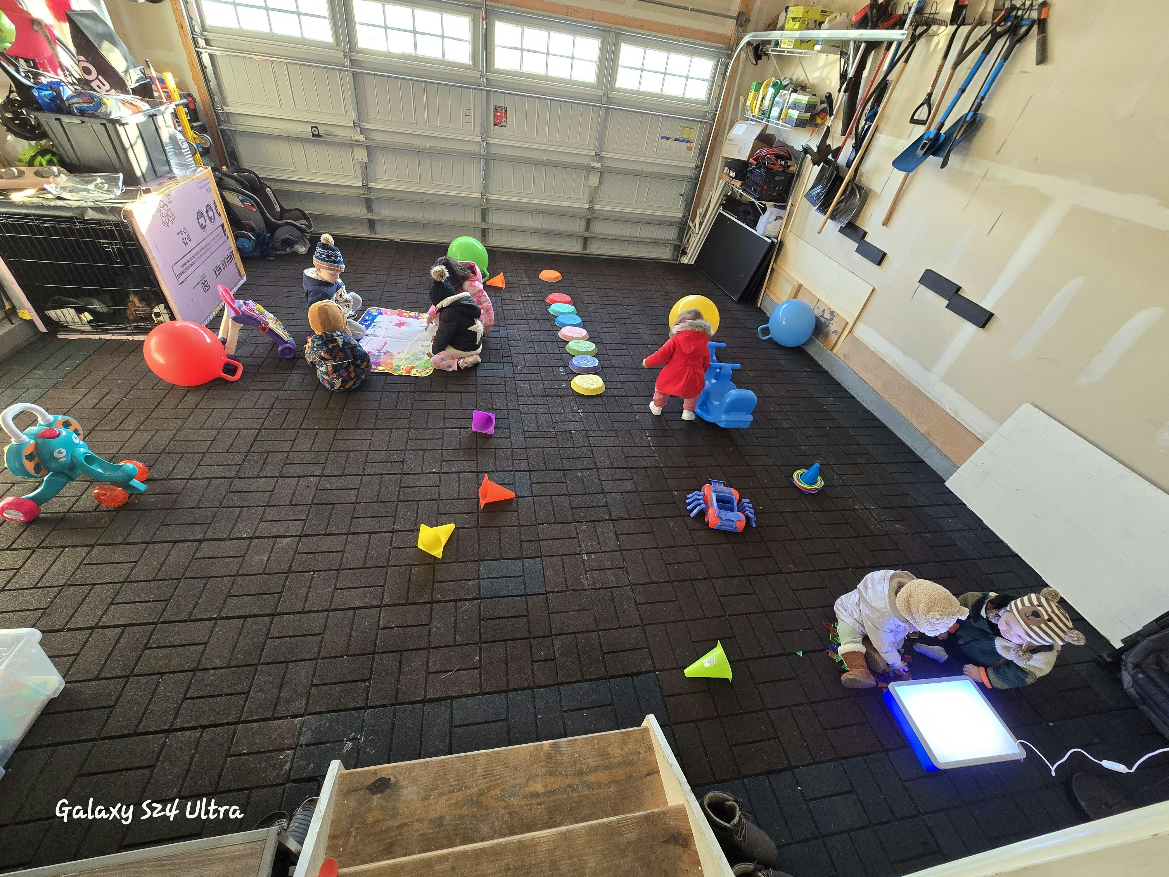 Children playing with toys on a dark tiled floor in a garage