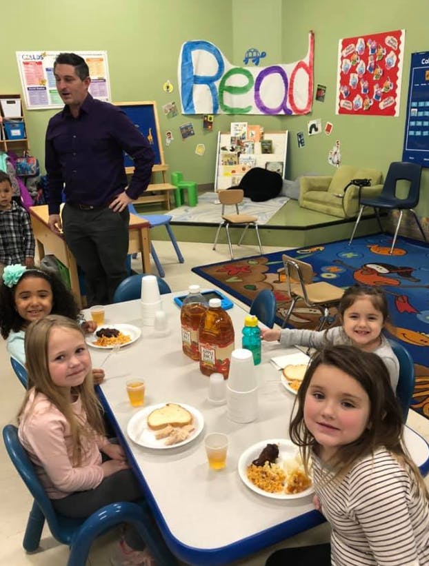 Adult and children in a classroom eating at a table