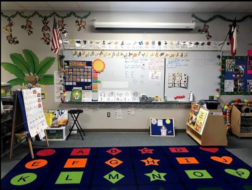 Empty classroom with a whiteboard, colorful rug, and learning materials