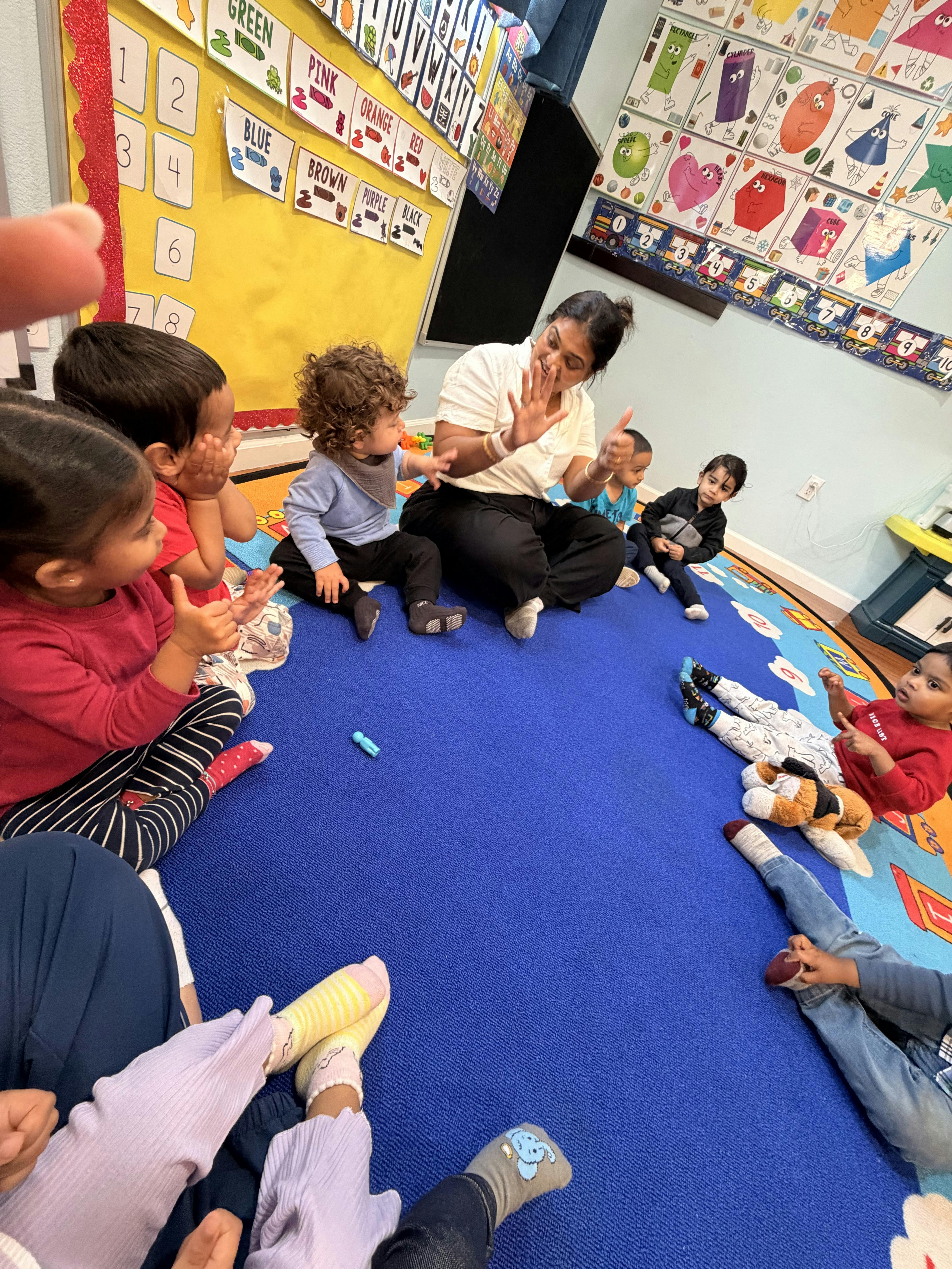 Adult sitting on a classroom floor in a circle with a group of children