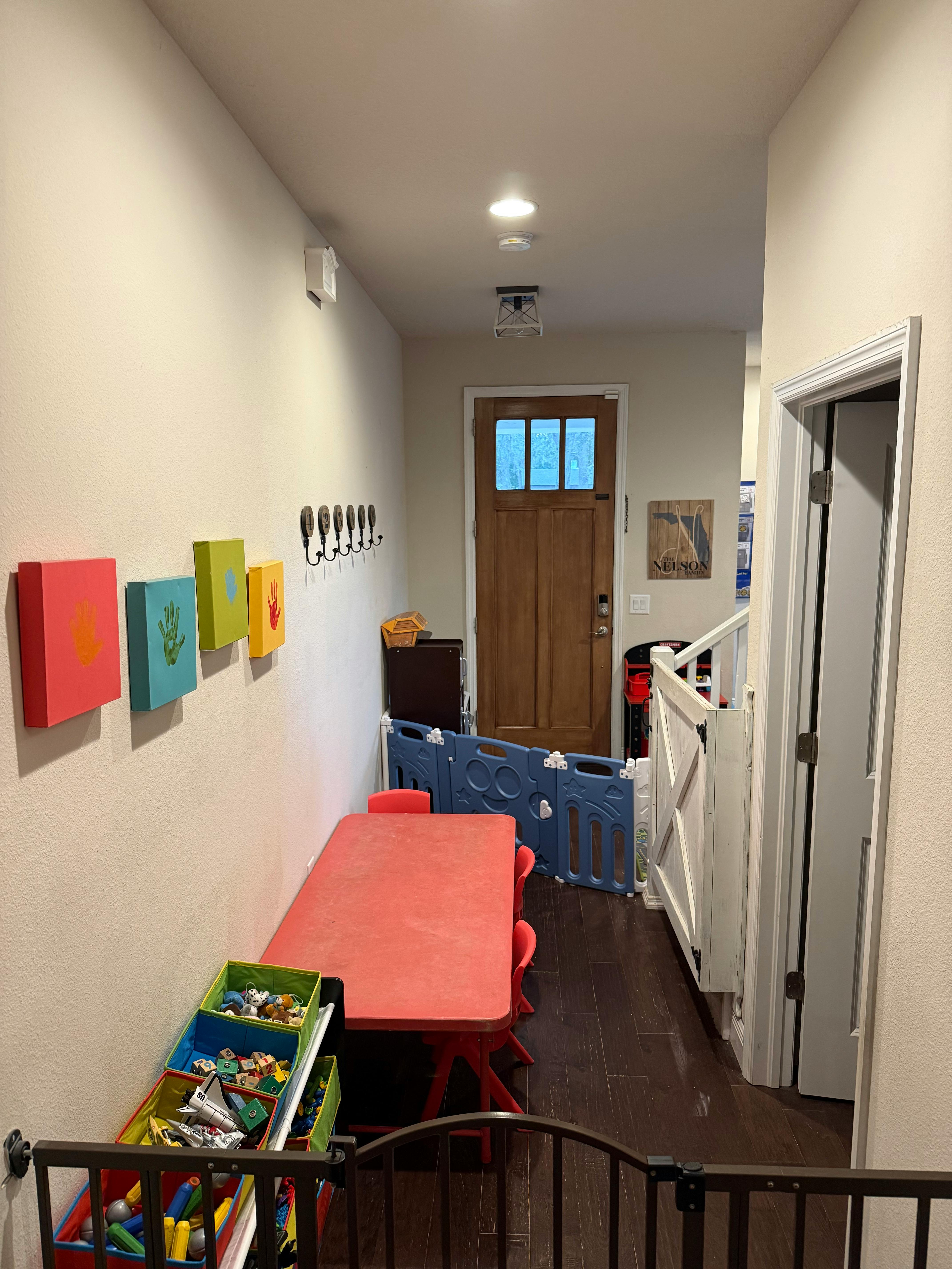 Hallway with a red table, toy storage, and a baby gate