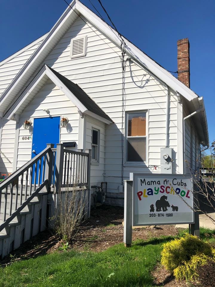 White house with a blue door and a sign for Mama n' Cubs Playschool