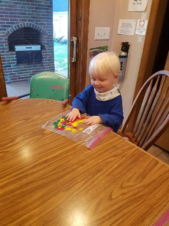 Child playing with colorful shapes in a plastic bag on a wooden table