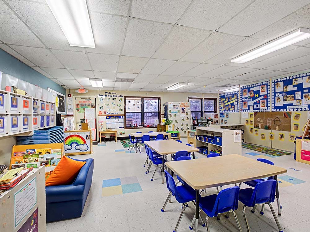 Classroom with small tables and chairs, shelves, and learning materials on the walls
