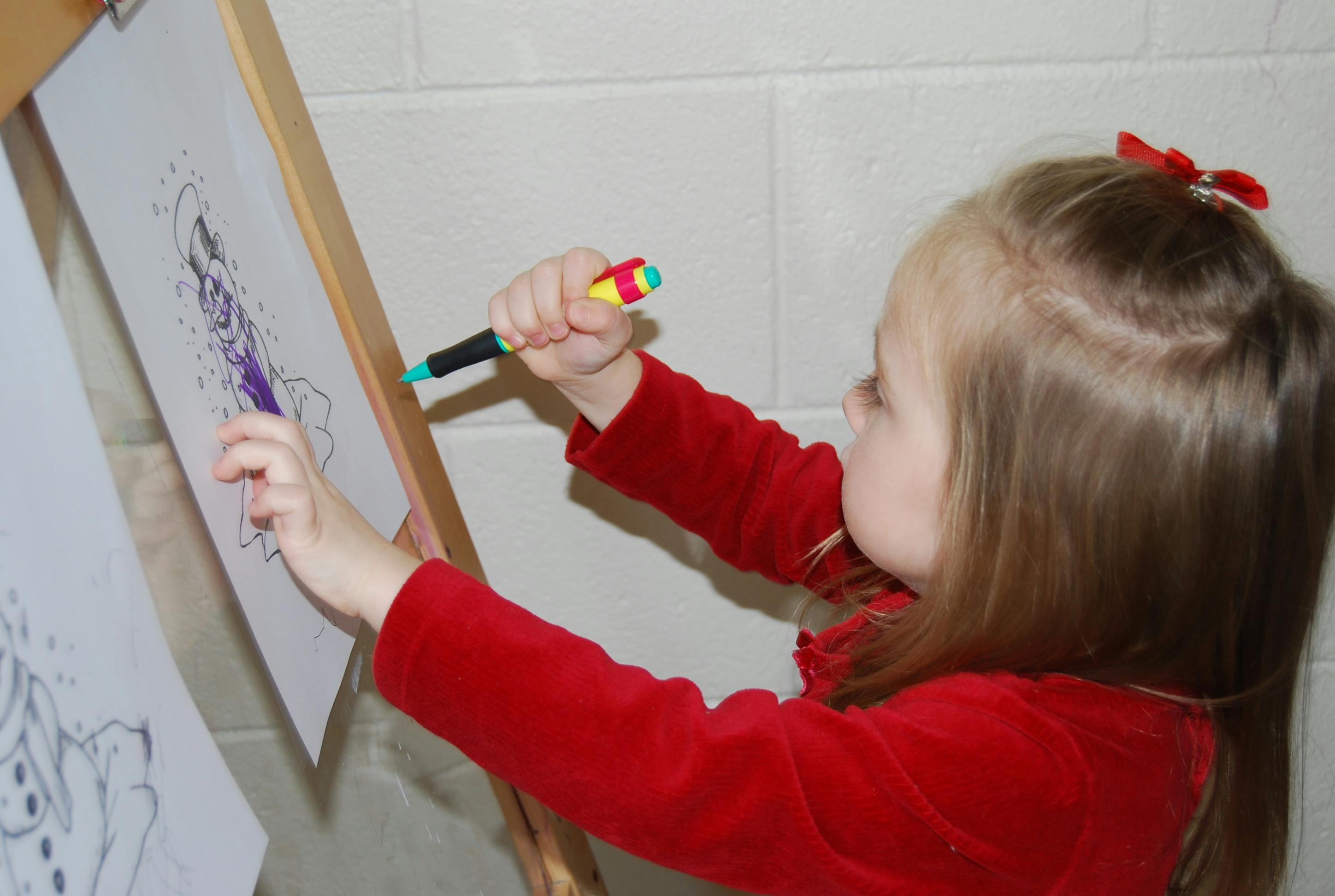 Child drawing on an easel with a marker