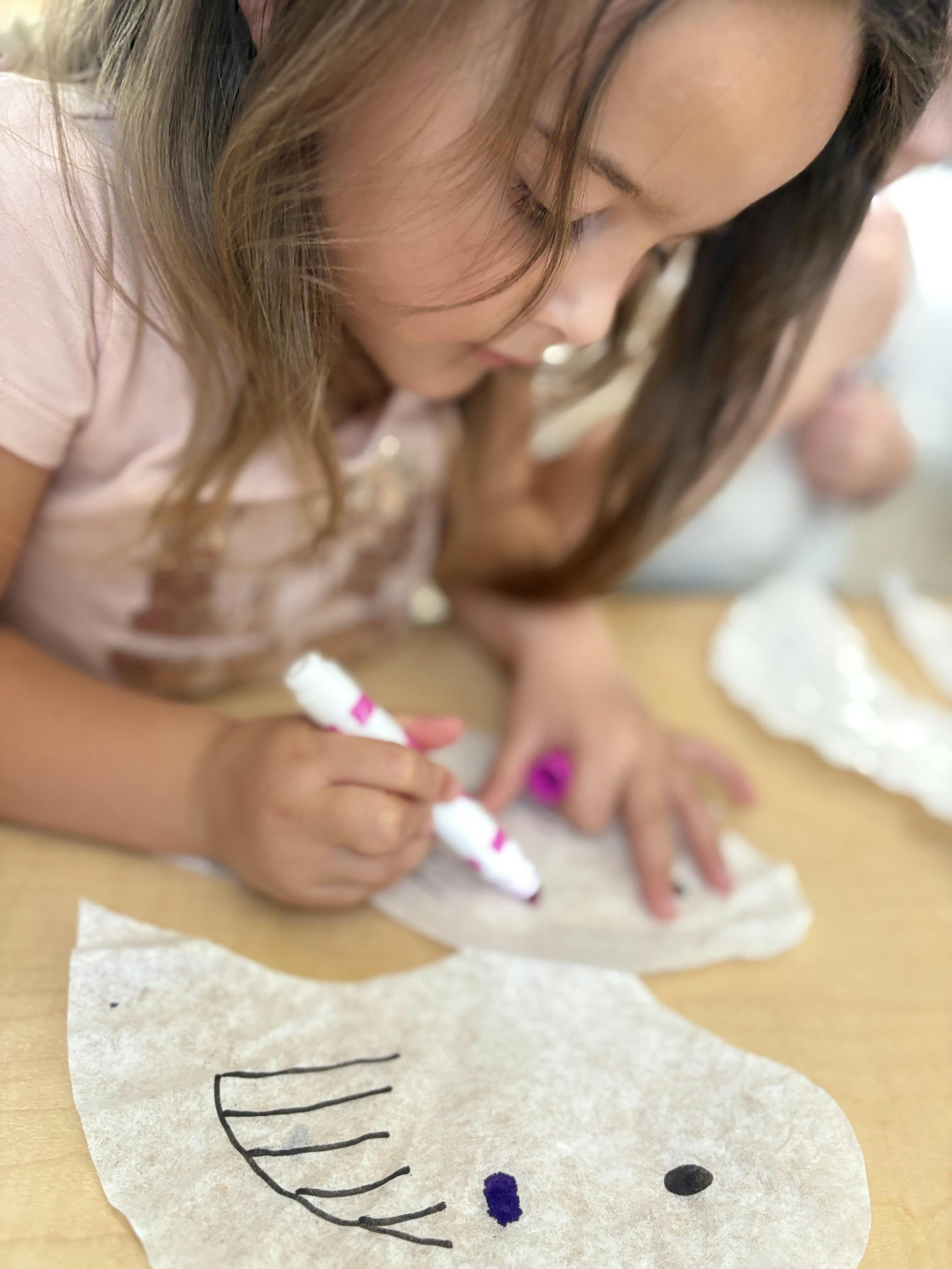 Child drawing on paper with a purple marker