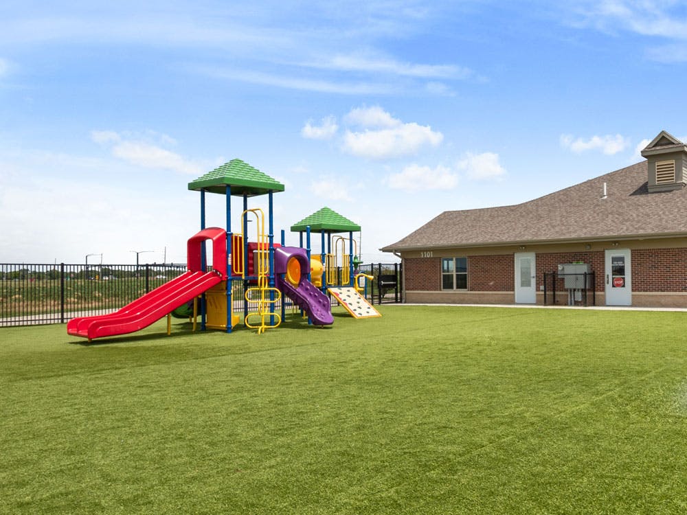 Playground with slides and climbing structures next to a brick building