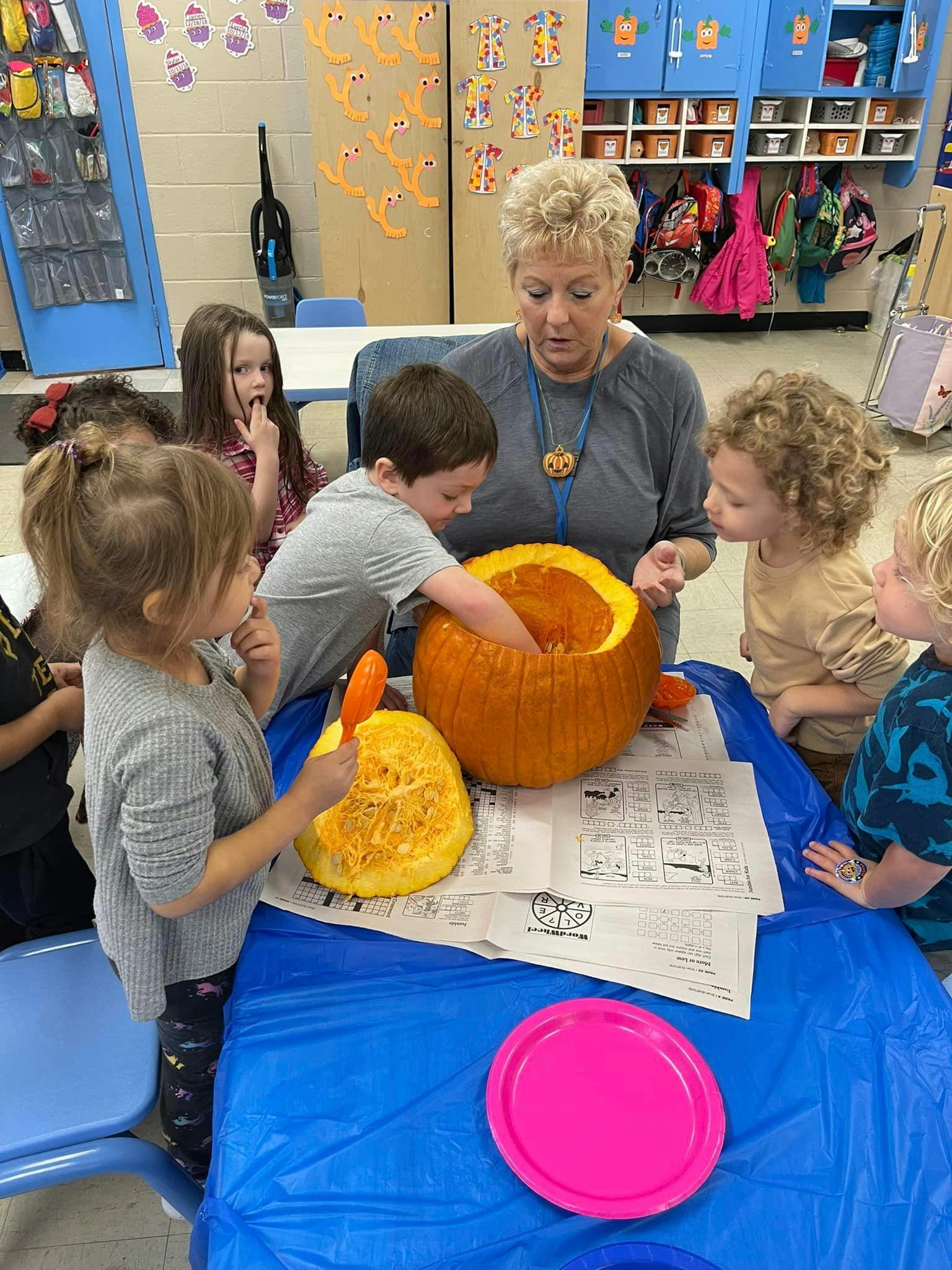 Adult and children carving pumpkins in a classroom