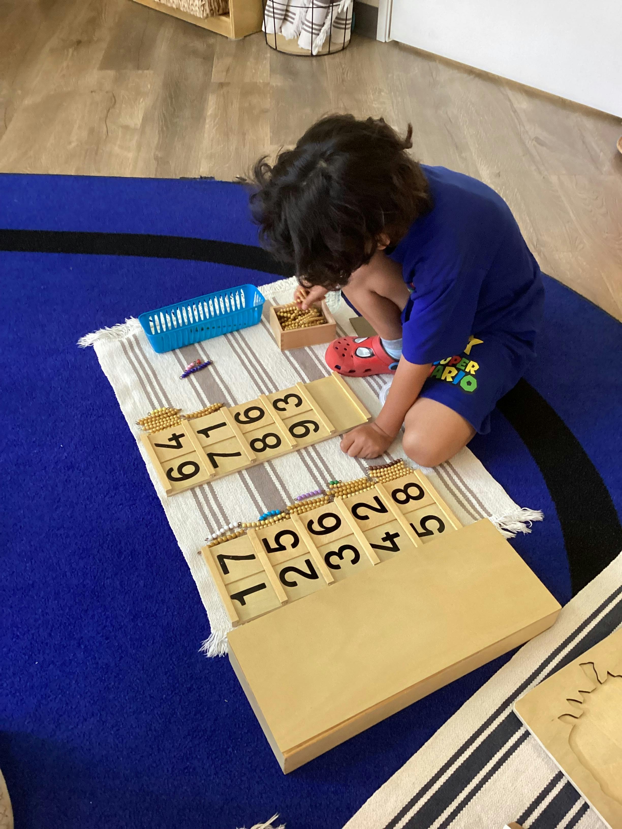 Child working with wooden bead math materials on a floor rug