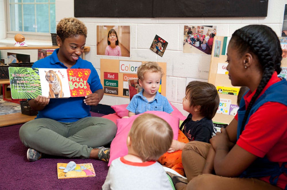 Two adults reading to children in a classroom