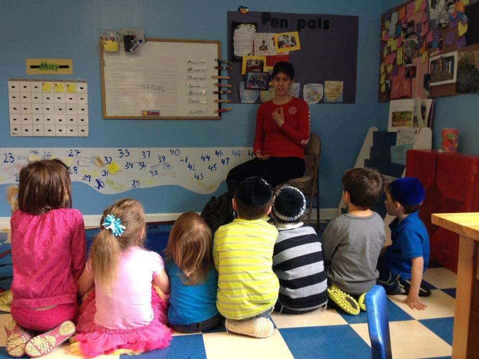Person sitting on a chair in front of children sitting on the floor