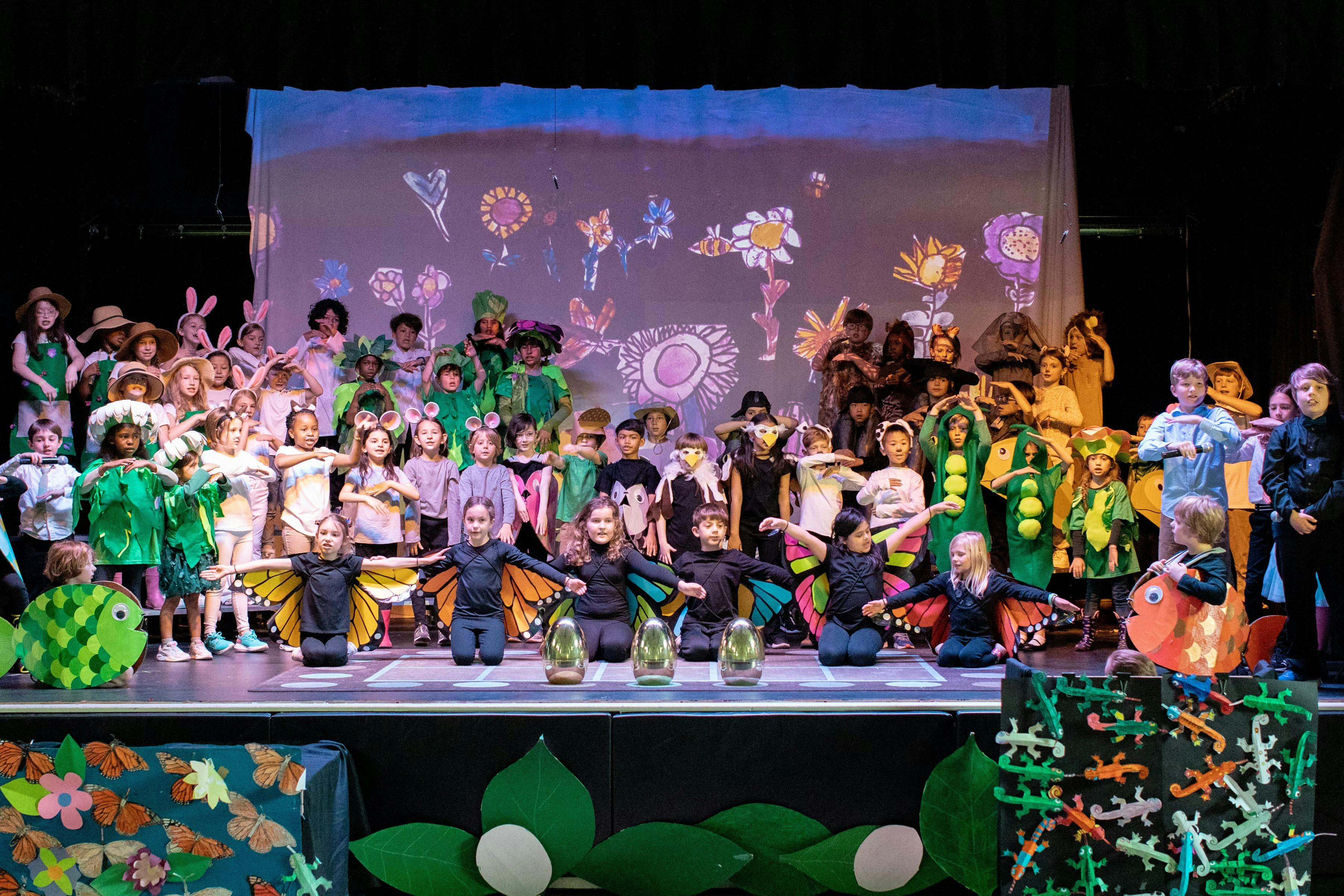 Children in costumes on a stage with a projected backdrop