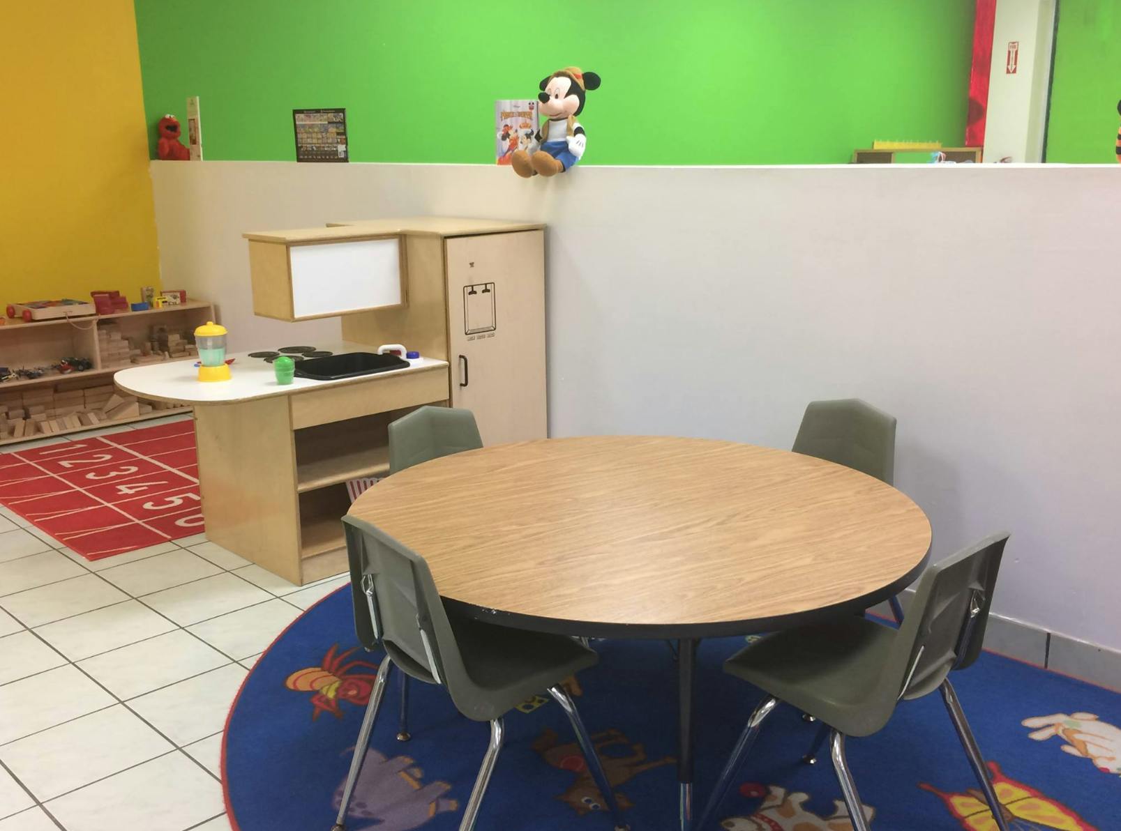 Classroom with a round table and chairs, and a play kitchen