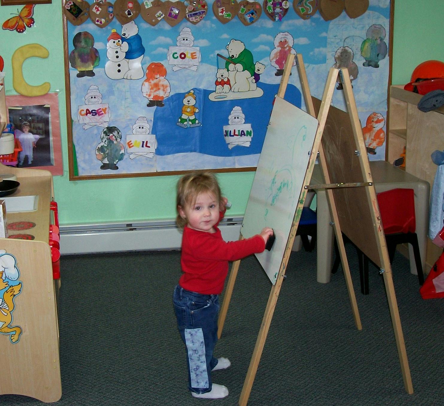 Child drawing on an easel in a classroom