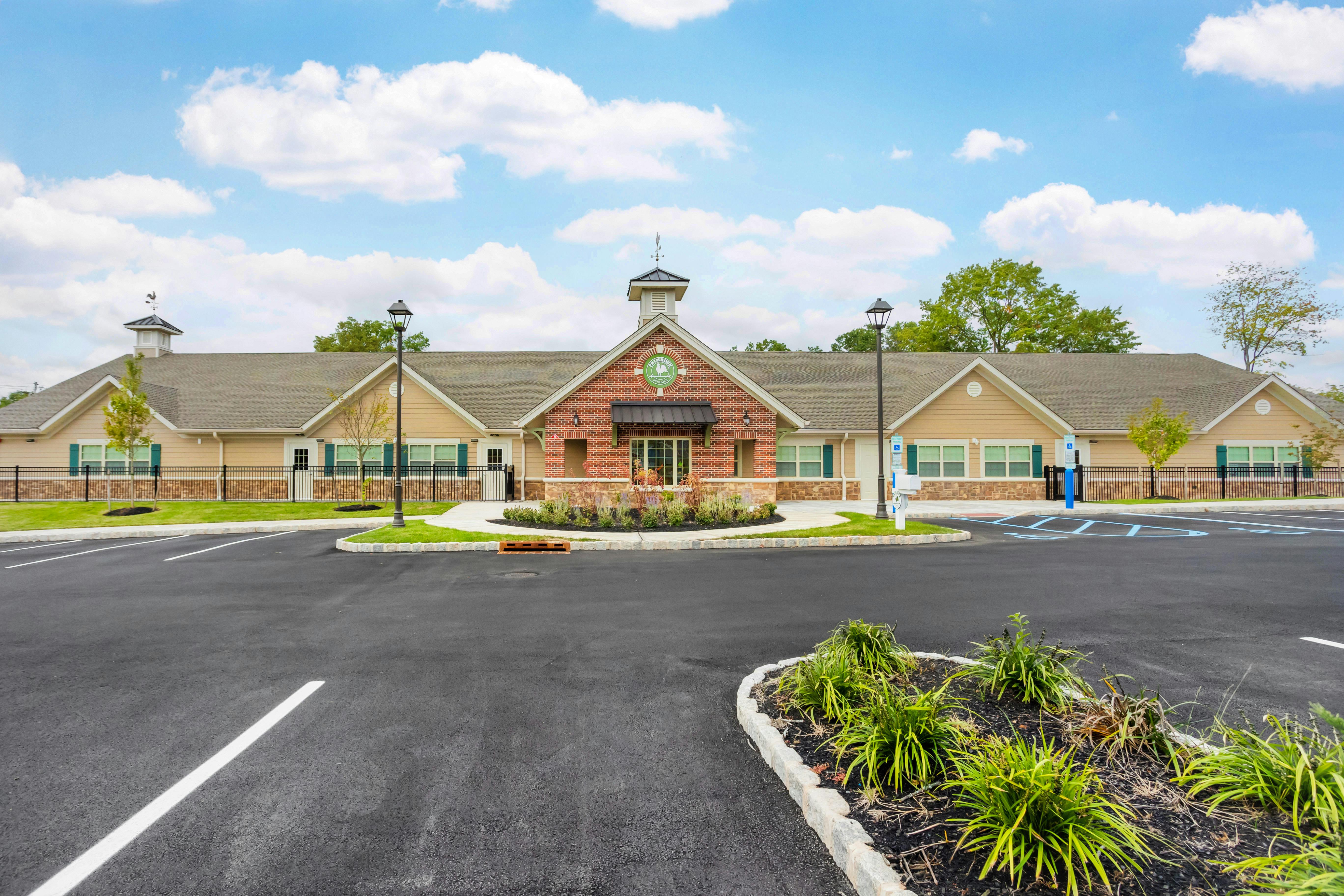 Single-story school building with brick and siding, a cupola, and a parking lot