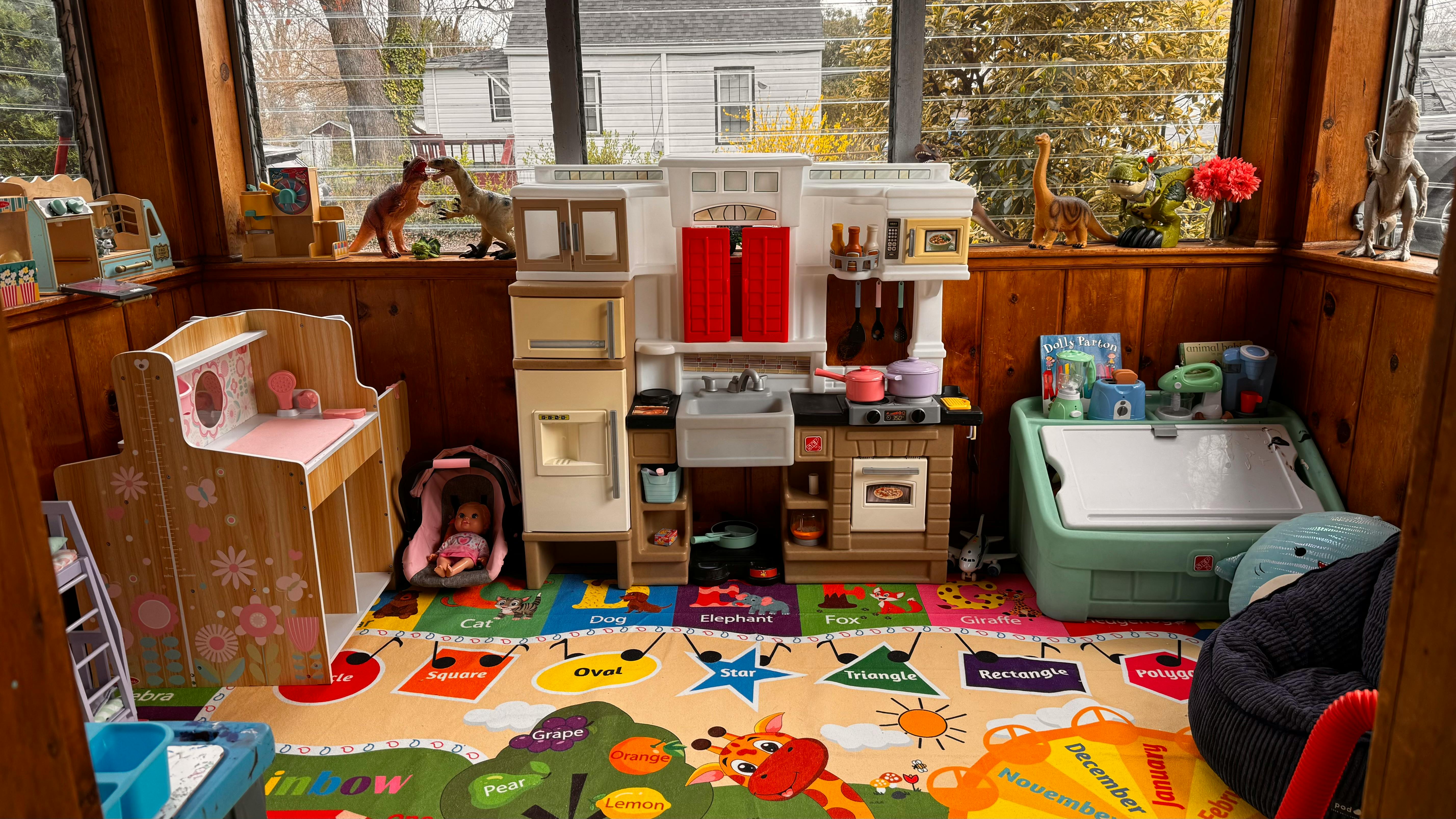 Playroom with toy kitchen, changing table, and colorful rug
