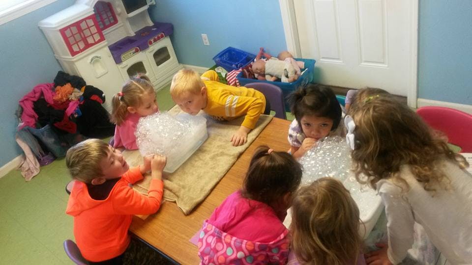Children gathered around a table with bubble wrap
