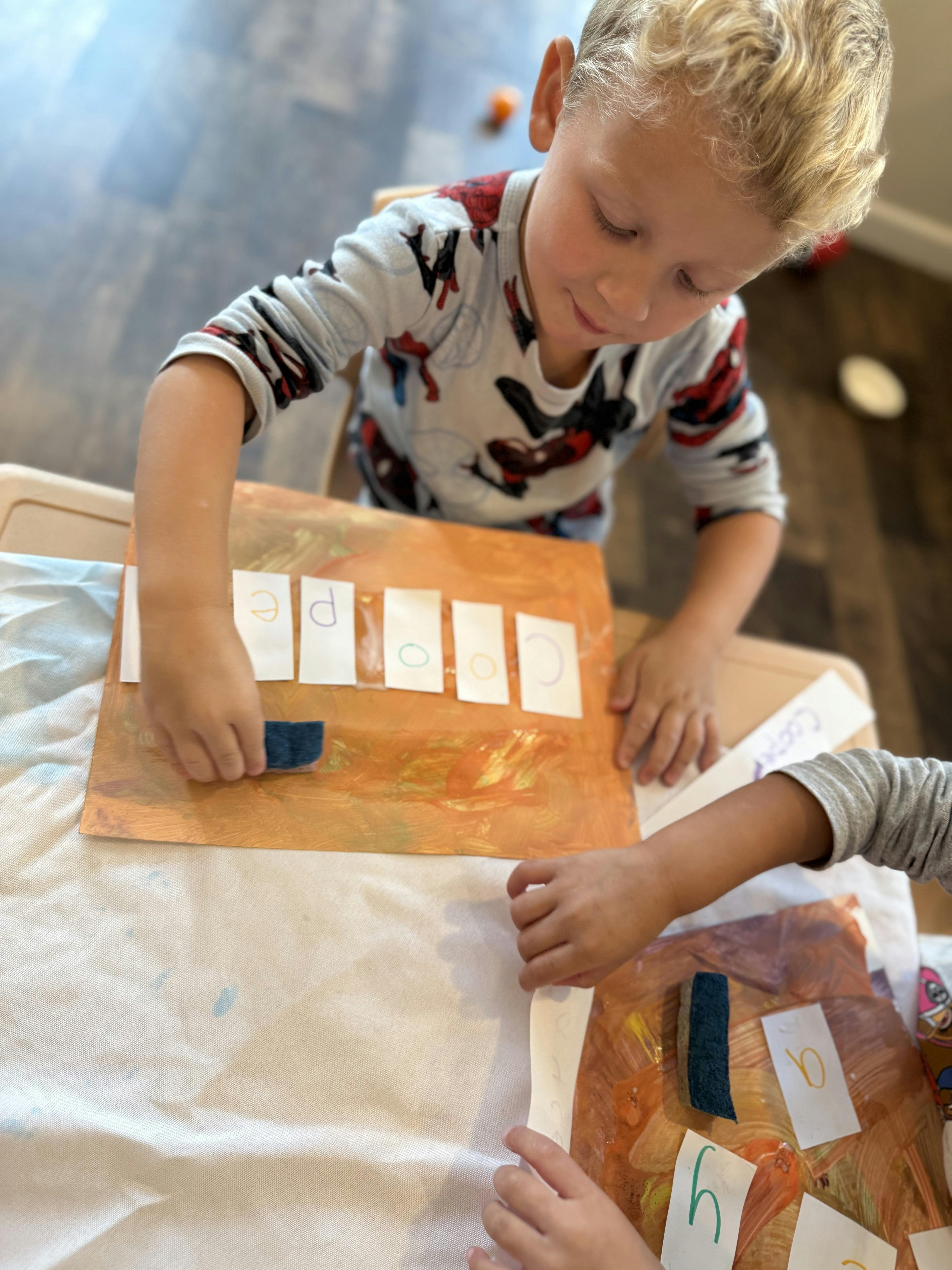 Child placing a blue object on a paper with letters