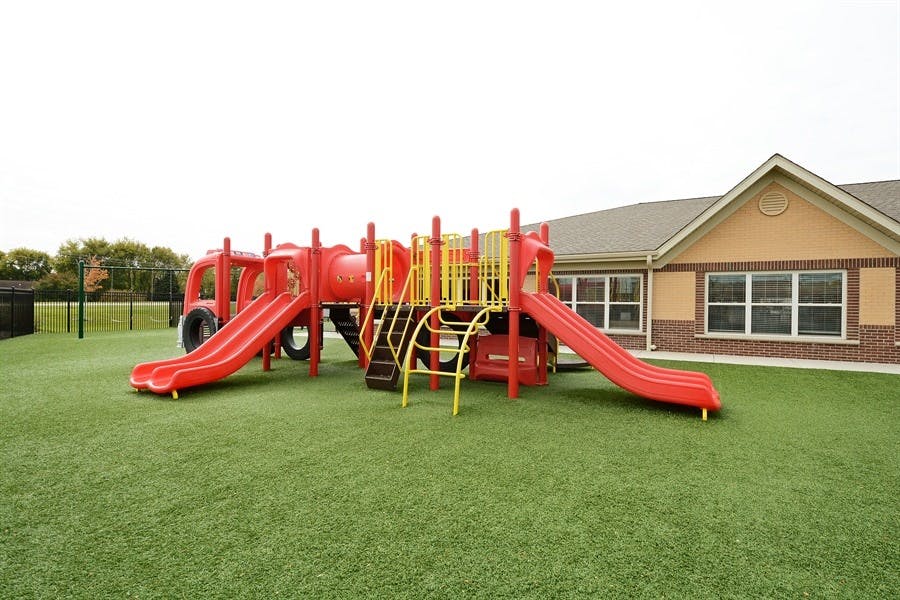 Red and yellow playground structure on green turf