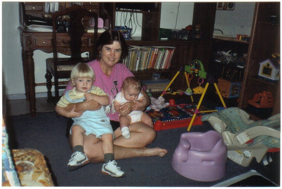 Person sitting on floor holding a child and an infant