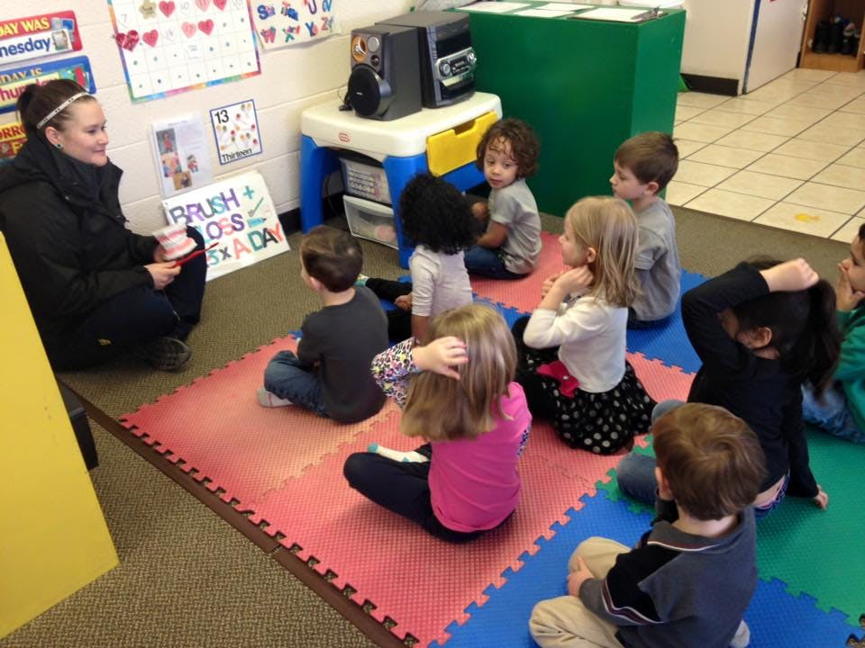 Adult reading to children sitting on floor in classroom