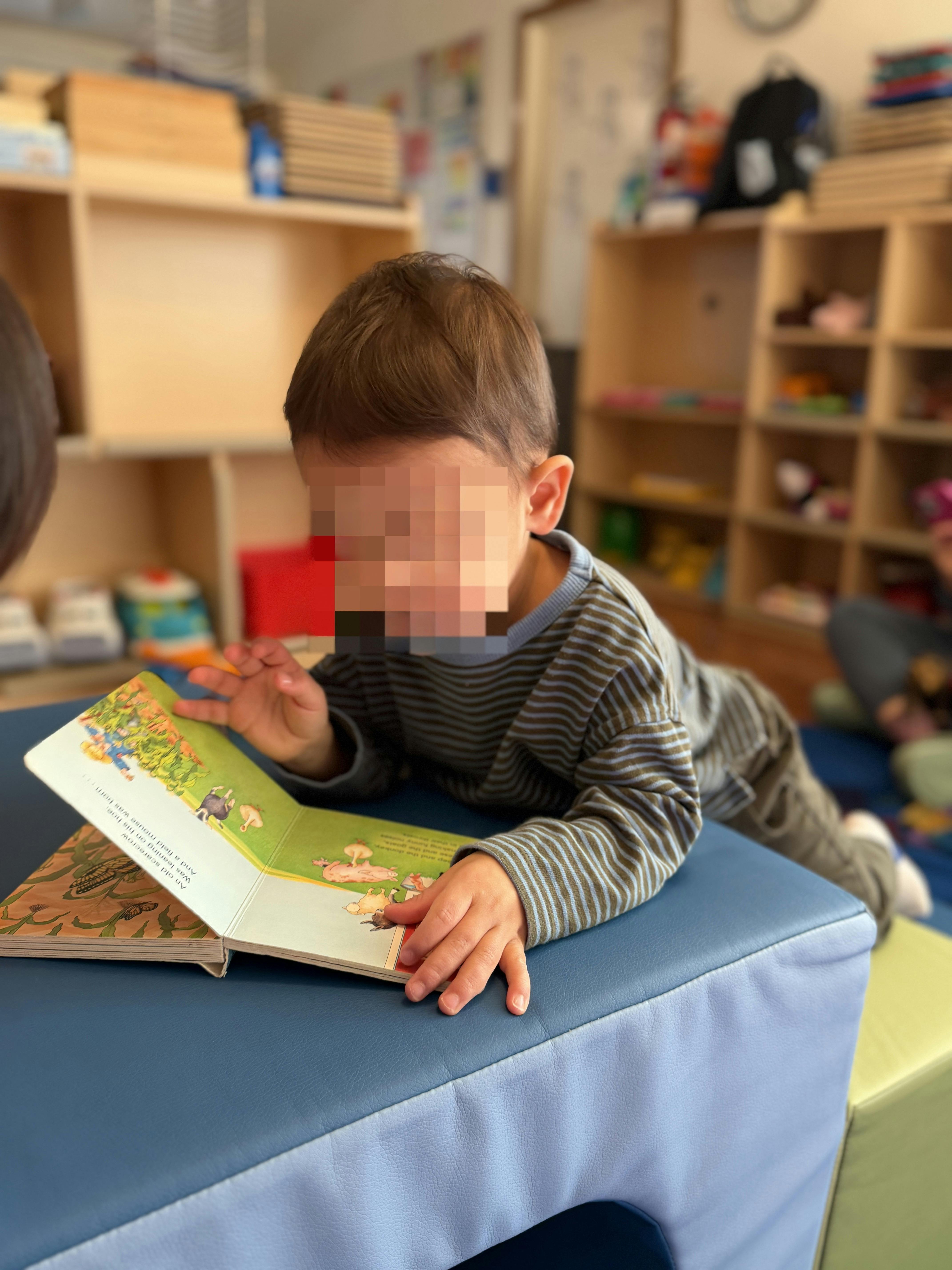Child lying down and looking at an open picture book