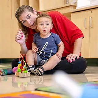 Adult and child sitting on floor with toy