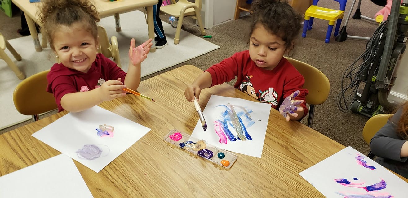 Two children painting at a table