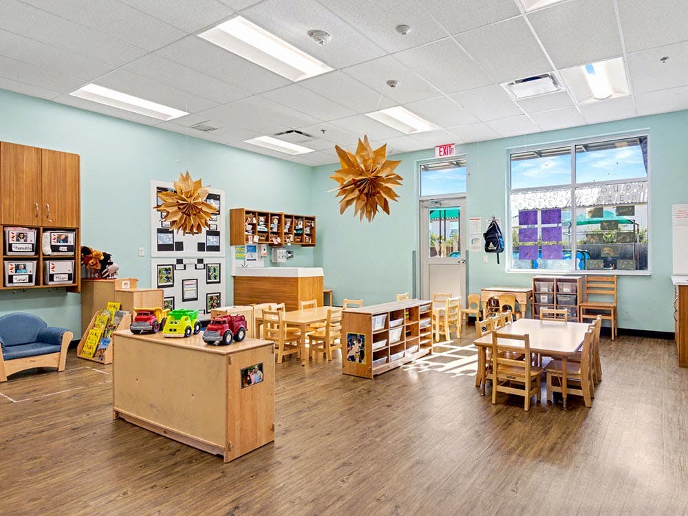 Classroom with small tables and chairs, toys, and cabinets
