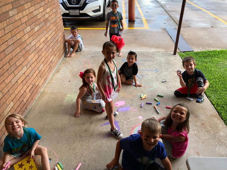 Group of children drawing with chalk on a sidewalk