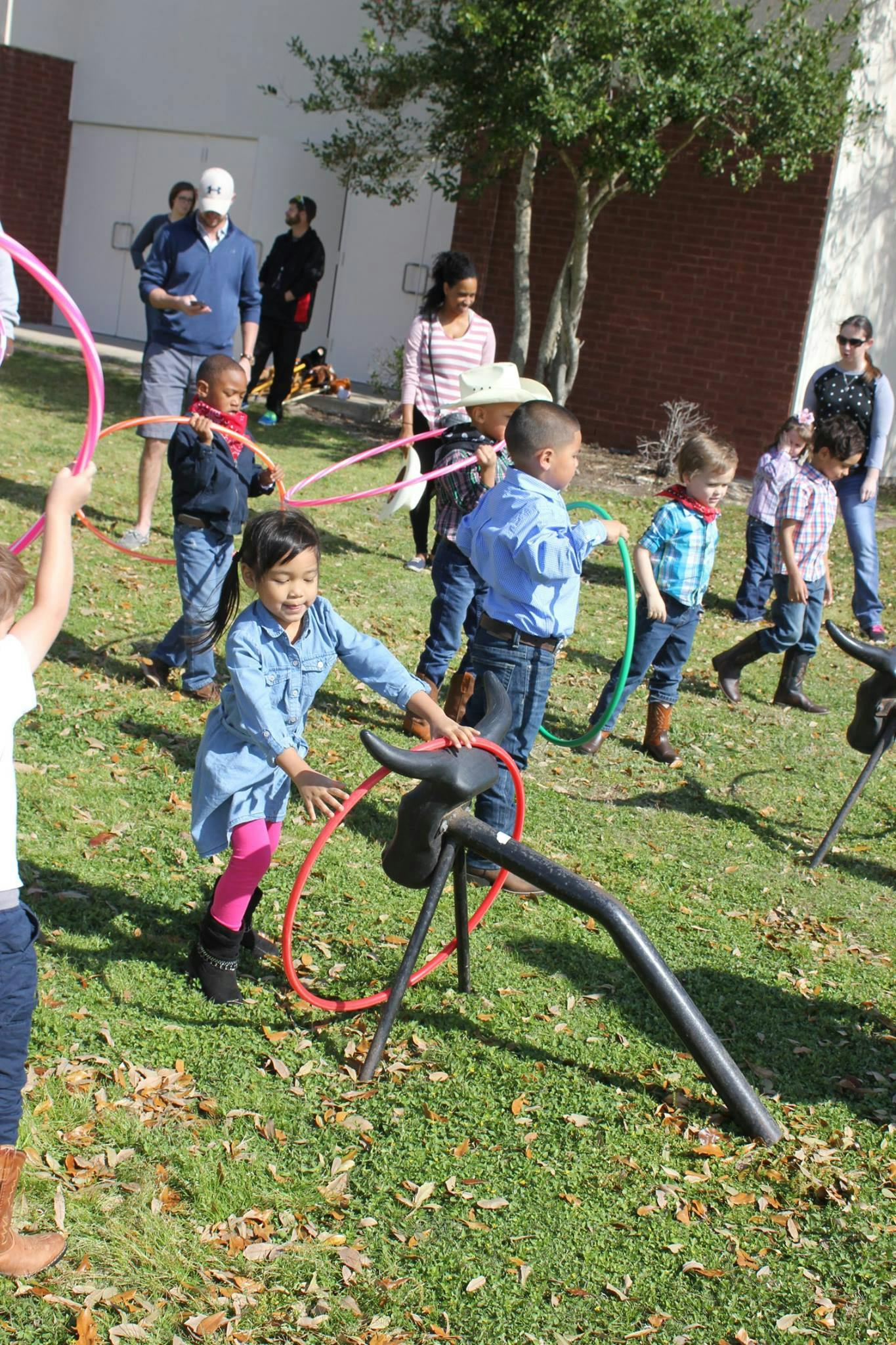Children playing with hula hoops and a bull riding game outdoors