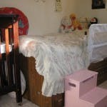 Bed with white bedding and a pink step stool next to it