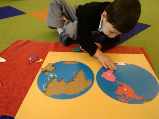 Child on floor playing with a world map puzzle