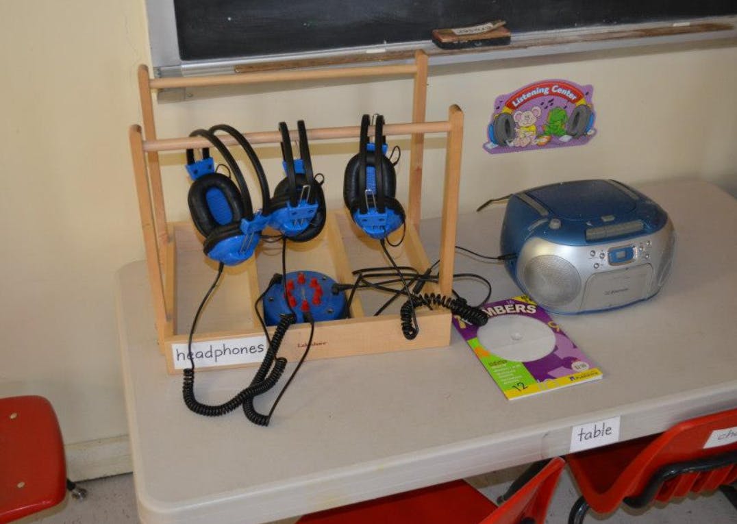 Headphones on a wooden rack next to a boombox on a table